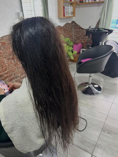 Antes del progresivo: pelo oscuro largo con frizz y ondas sueltas, en el sillón del estudio